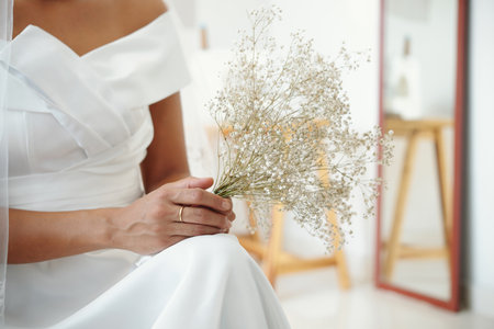 Small bouquet in hands of bride in white dressの写真素材