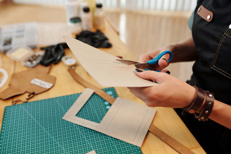 Craft person cutting out cardboard patterns for leather itemの写真素材