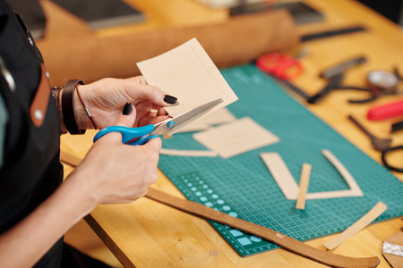 Hands of creative woman cutting out cardboard patterns with sharp scissorsの写真素材