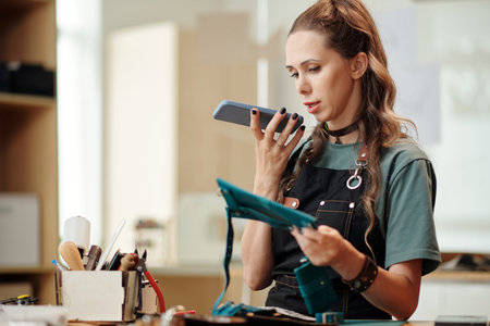Craftsperson recording voice message for customer who ordered small leather bag