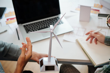 Team of sustainable energy engineers discussing model of wind turbine for new big projectの写真素材
