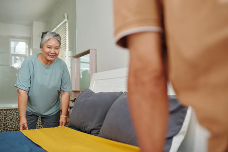 Senior couple making bed in the morningの写真素材