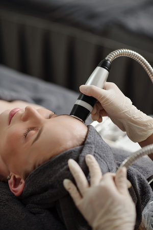 Young woman getting rf-lifting procedure in spa salon