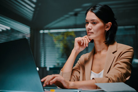 Portrait of serious pensive young businesswoman reading data on laptop screenの写真素材