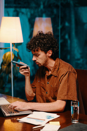 Businessman listening to voice message from colleague when working on laptop