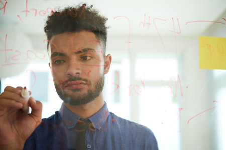 Portrait of businessman writing important data on glass wall preparing for brainstorming sessionの写真素材