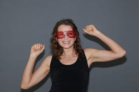 Portrait of joyful mature woman in red glasses dancing in party