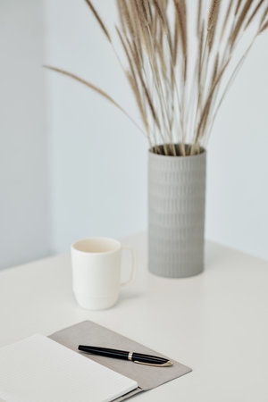 Opened planner and cup of coffee on desk in minimalistic officeの写真素材