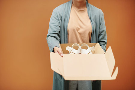 Studio portrait of saleswoman opening box with leather sandals
