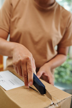 Woman with sharp paper knife unpacking delivered boxes