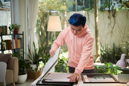 Creative young man putting black and white printed photos in frames