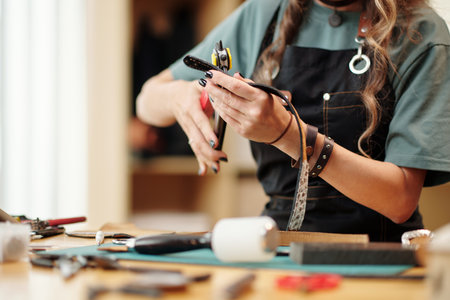 Woman using rotary punch tool for making holes in leather beltの写真素材