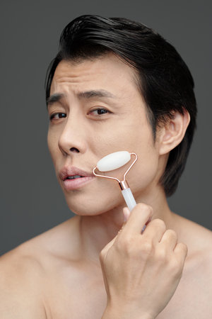 Man massaging face with quartz roller to get rid of wrinklesの写真素材