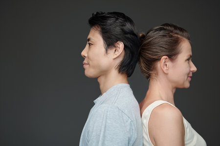 Man and woman standing back to back, isolated on greyの写真素材