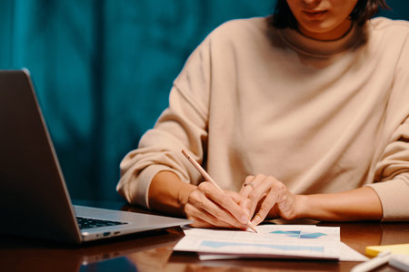 Businesswoman correcting chart in report when working at office desk