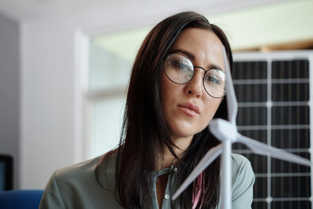 Pensive woman looking at wind energy project model created for investor
