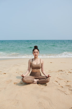 Young woman meditating on beach in the morningの写真素材