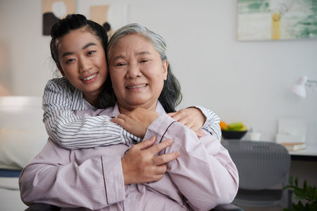 Joyful young woman hugging grandmother when visiting her in nursing home
