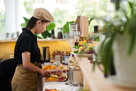 Serious cafe cook cutting fruits for making breakfast smootheis