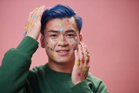 Portrait of joyful young man with stickers on face and handsの写真素材