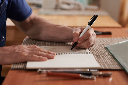 Glass worker drawing wavy line in notepad when working on sketches for new project