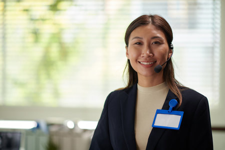 Portrait of positive businesswoman with empty badge on jacket smiling at cameraの写真素材