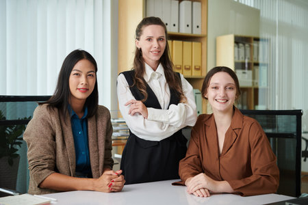 Portrait of team of businesswomen smiling at camera while working together in officeの写真素材