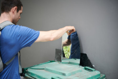Young man collecting broken mirror for recycling or to make artwork from glassの写真素材