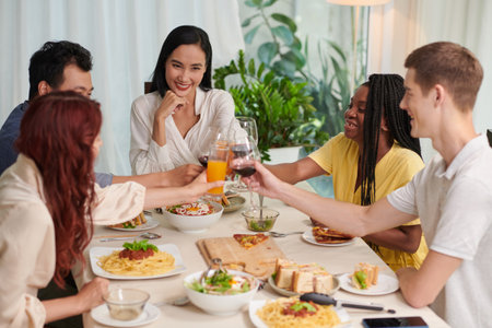 Happy group of friends toasting over dinner tableの写真素材