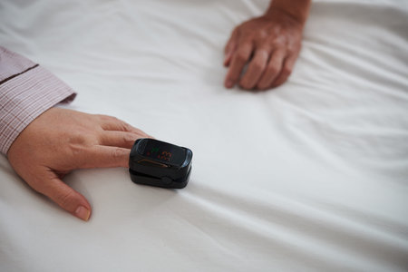 Senior woman with oximeter on finger checking oxygen level in her blood