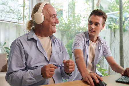 Young man sharing music playlist with grandfatherの写真素材