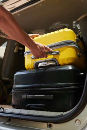 Closeup image of airport transfer driver taking suitcases out of car trunkの写真素材