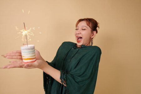 Excited transgender woman holding rainbow candle with burning bengal light, celebrating pride month