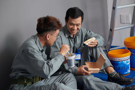 Builders eating instant noodles and sandwiches for lunch at construction siteの写真素材