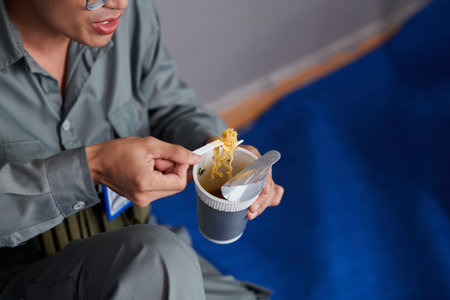 Worker eating instant noodles for lunch at construction siteの写真素材