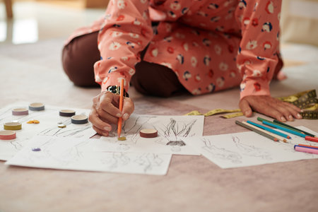 Fashion designer sitting on floor in her studio and drawing sketchesの写真素材