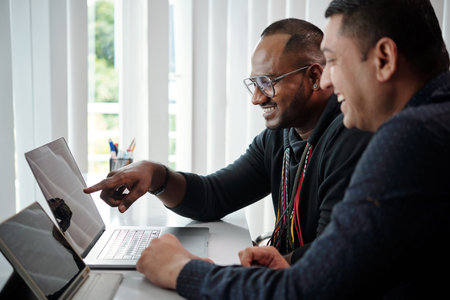 Team of software developers checking programing code on laptop screen