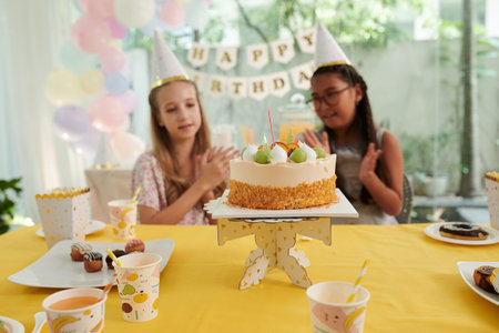 Birthday party guests clapping to decorated cake brought to table