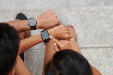 Fit young people checking data in fitness trackers after morning jogの写真素材
