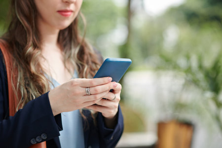 Cropped image of serious businesswoman answering text messages from coworker or reading notificationsの写真素材