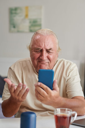 Portrait of unhappy senior man video calling his friend to discuss problems