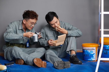 Workers eating lunch after painting walls in house of client