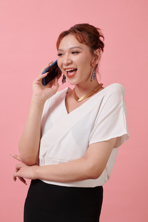 Excited elegant transgender woman talking on phone with best friendの写真素材