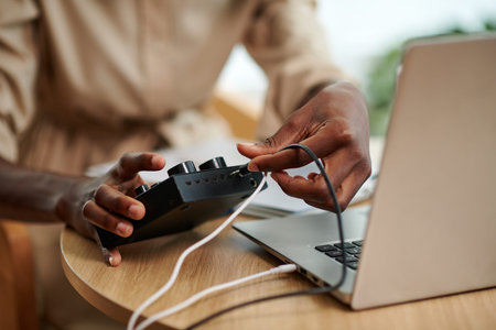 Hands of podcaster inserting cord in amplifier