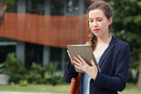 Portrait of positive businesswoman reading report on tablet computerの写真素材