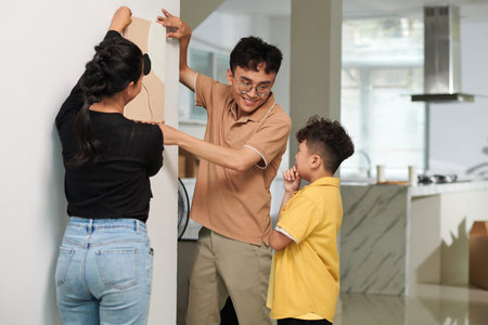 Parent asking son to check if the picture is hanging straightの写真素材