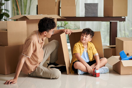 Preteen boy and his father playing together in new apartment after unpacking belongings