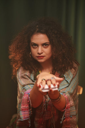 Portrait of serious fortune teller asking client to take tarot card from her handsの写真素材