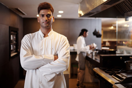 Portrait of confident restaurant chef in white uniform standing in fancy kinchenの写真素材