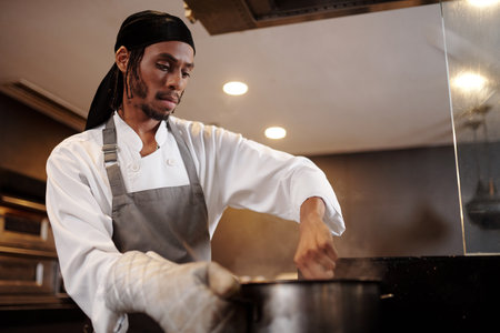 Serious cook mixing boiling soup in big saucepanの写真素材
